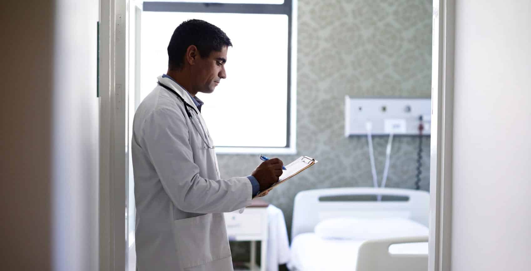 Male Doctor Filling Out Medical Forms Stock Photo