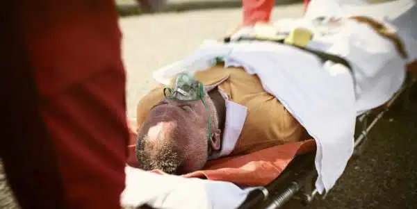 An elderly man on a stretcher with an oxygen mask.