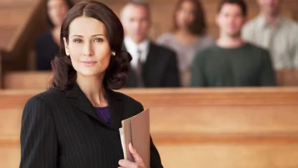 An attorney stands in front of the jury, holding a folder of court documents close by her side.