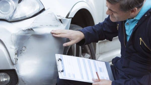 A mechanic completing an insurance estimate on a damaged vehicle.