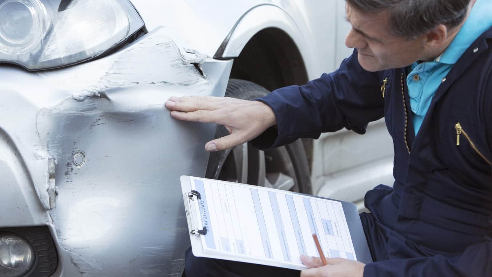 Auto Body Mechanic Examining Car Accident Damage Stock Photo