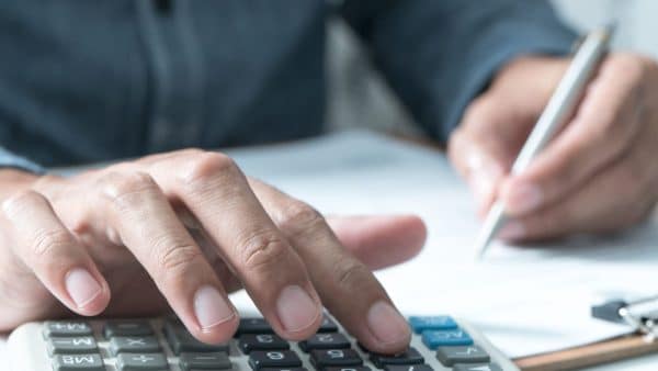 Man using a calculator and reviewing paperwork to estimate his SSDI disability payments.