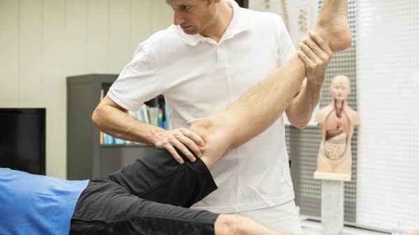 A medical professional extends the leg of an injured worker to test mobility.