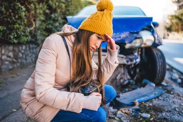 A worried woman sits in front of her damaged car after an accident in Chattanooga.