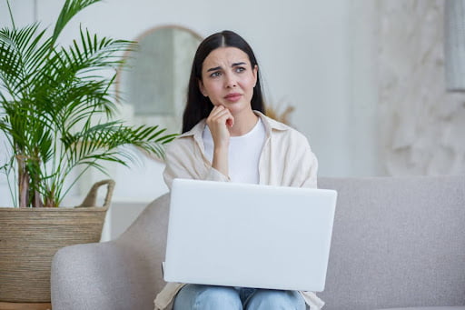 A woman sits at her laptop considering whether she needs a lawyer for a personal injury lawsuit.