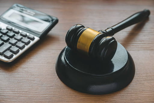 A calculator sits next to a gavel on a desk.