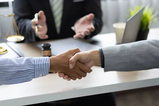 Two parties in a Tennessee personal injury lawsuit shake hands while a third-party mediator is seen in the background.
