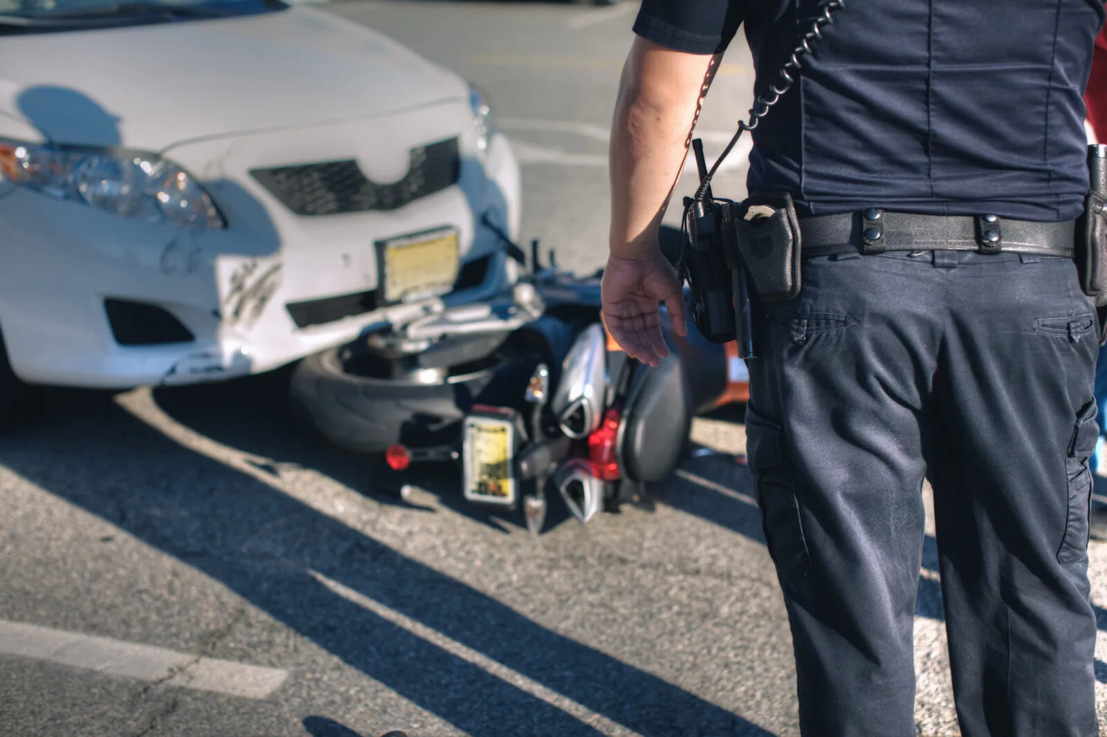 A police officer observes a slightly damaged vehicle that has collided with a motorcycle.