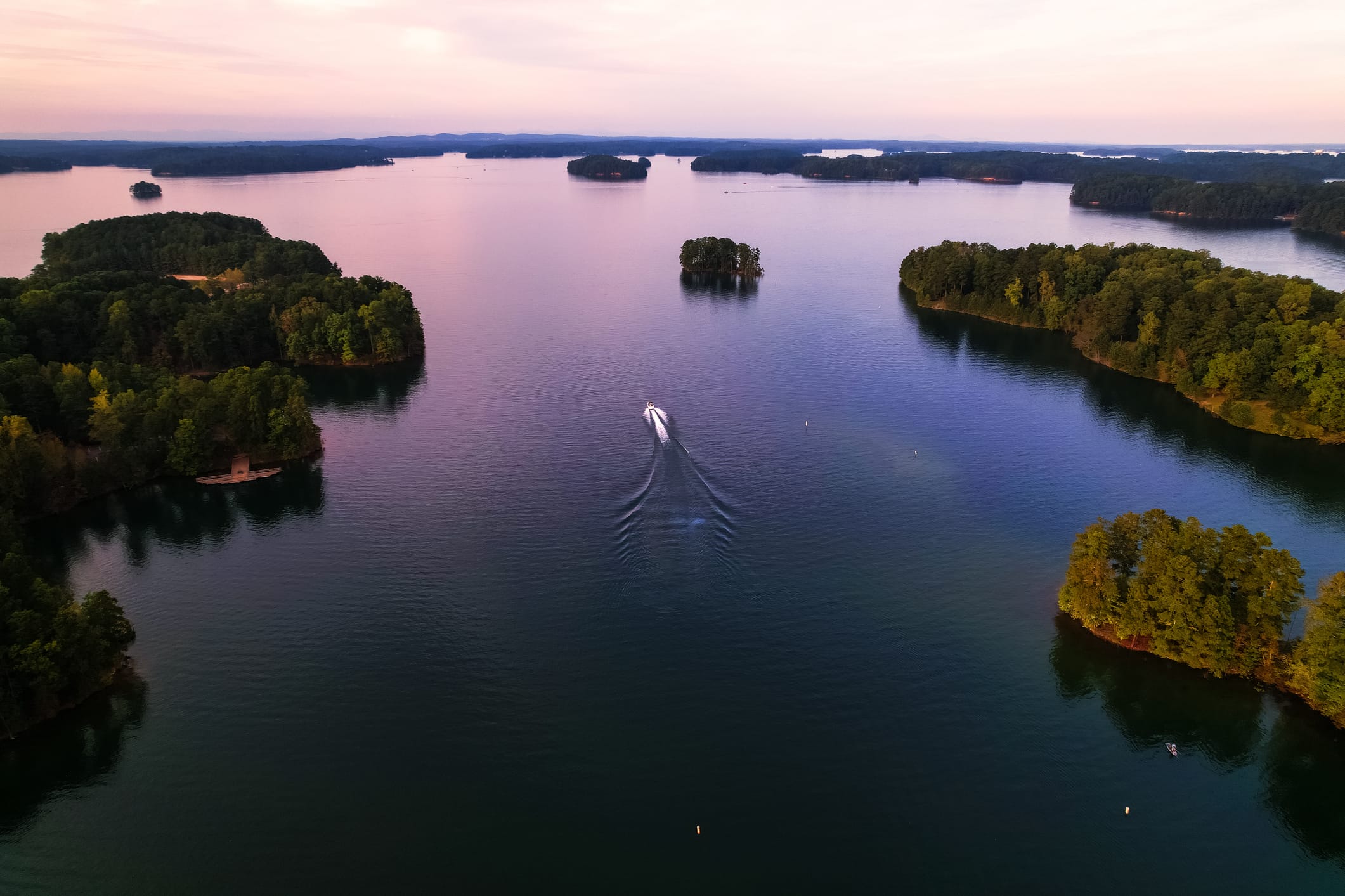 A boat on a lake in Georgia, with islands surrounding it.