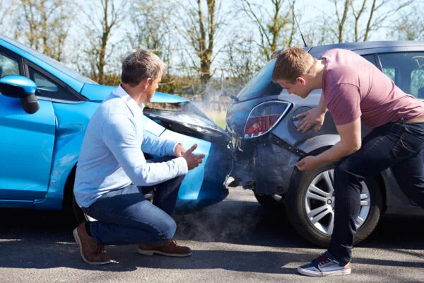 Two individuals evaluate the damage to their vehicles after an accident.
