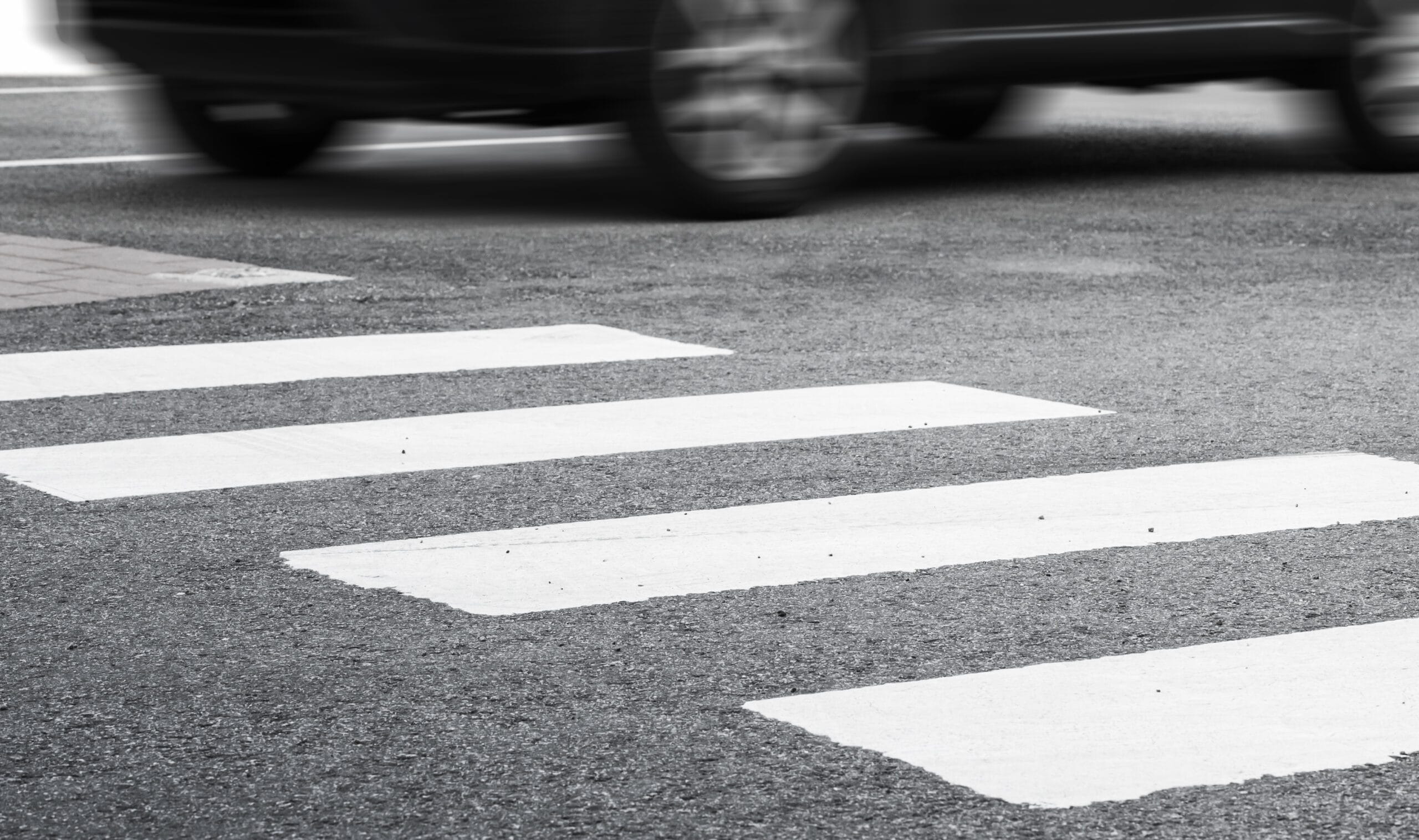 A crosswalk with a car speeding through.