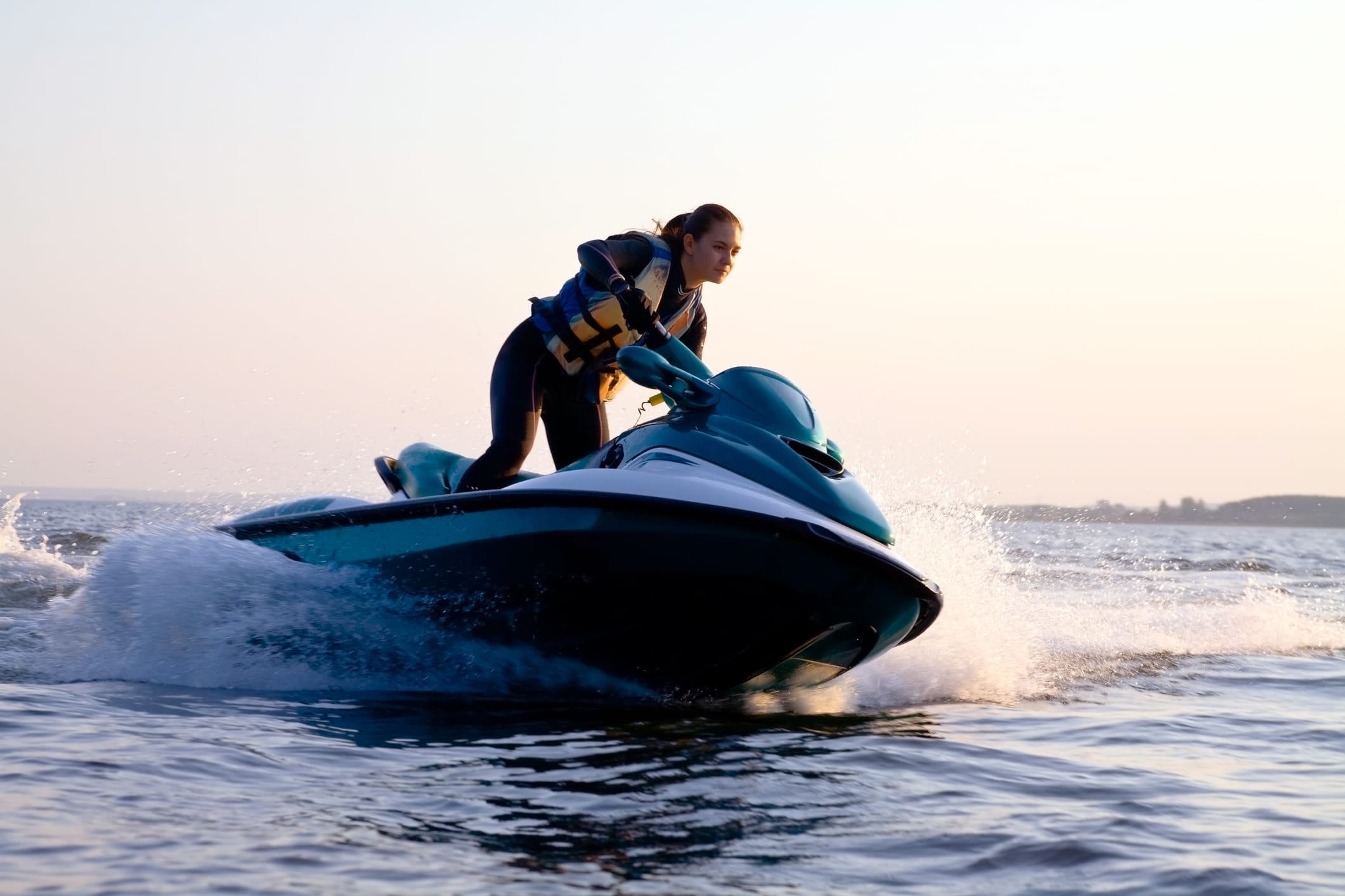 A person wearing a lifejacket is maneuvering a jet ski through the lake.