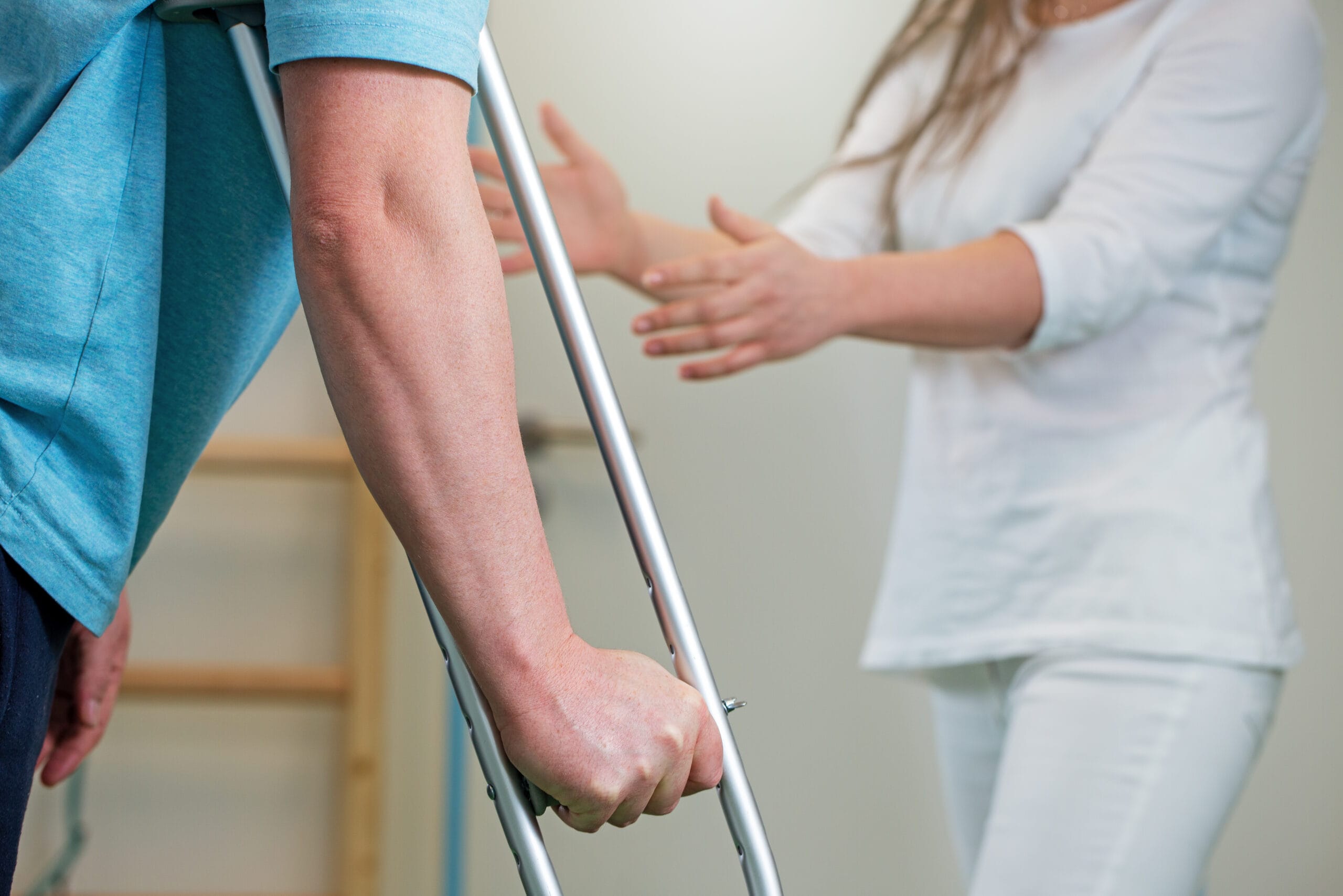 A physical therapist assists a patient on crutches.