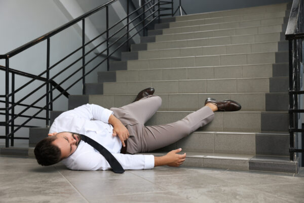 A businessman has fallen down a set of stairs in a public building.