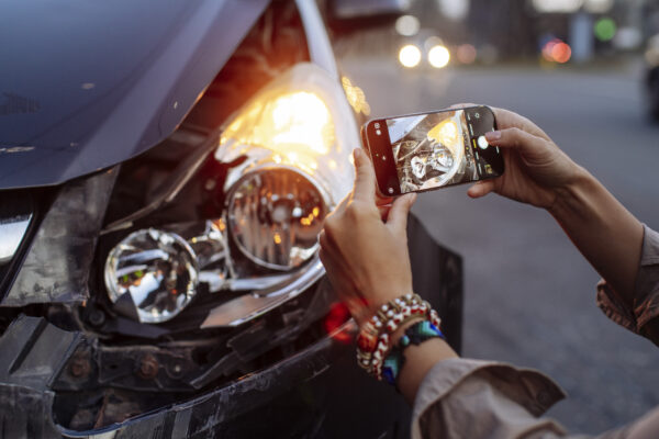 A person uses their phone to take pictures of their damaged vehicle for an insurance claim.
